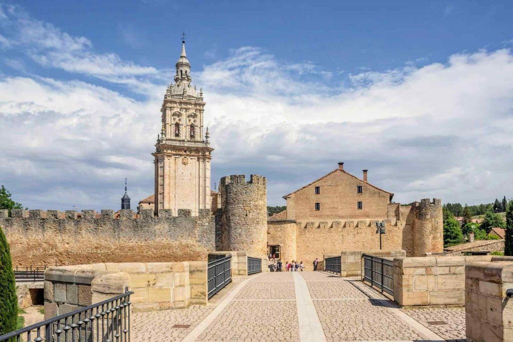 Entrada a un recinto medieval con murallas y torre de iglesia en la provincia de Burgos