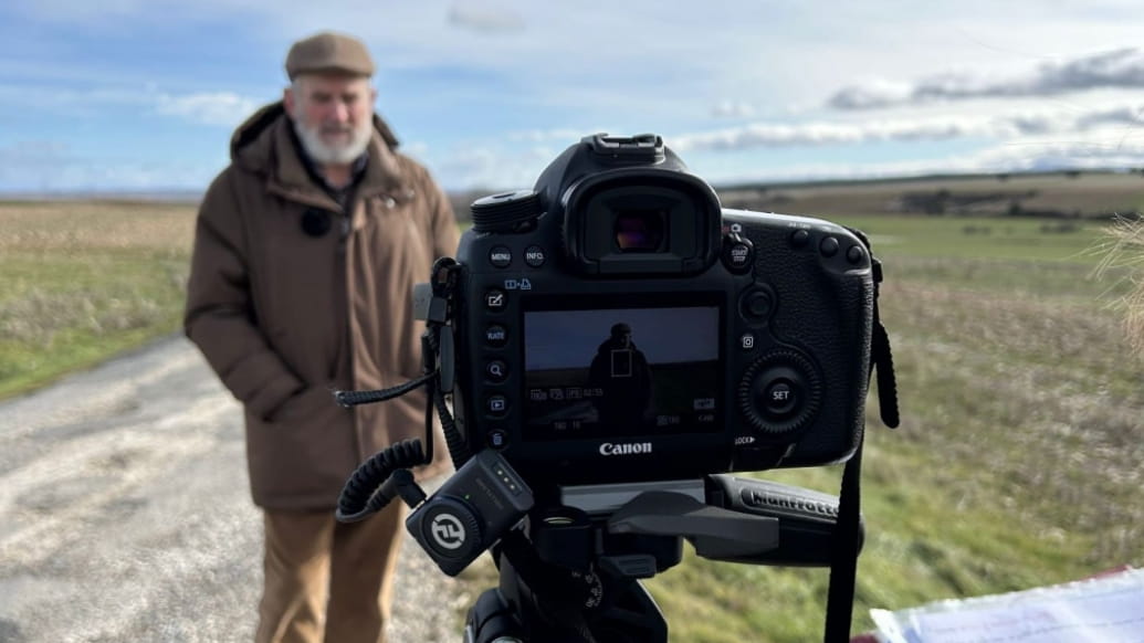 Cámara en primer plano grabando a un hombre en un paisaje rural de la España vaciada para un documental.