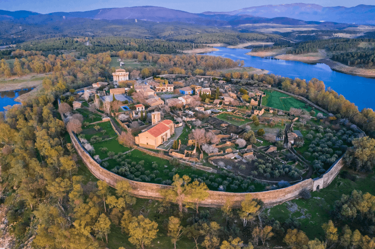 Pueblo de Granadilla desde una vista superior, mostrando que es una península amurallada sobre un embalse. Se observan sus alrededores con árboles y en el pueblo casas y campos.