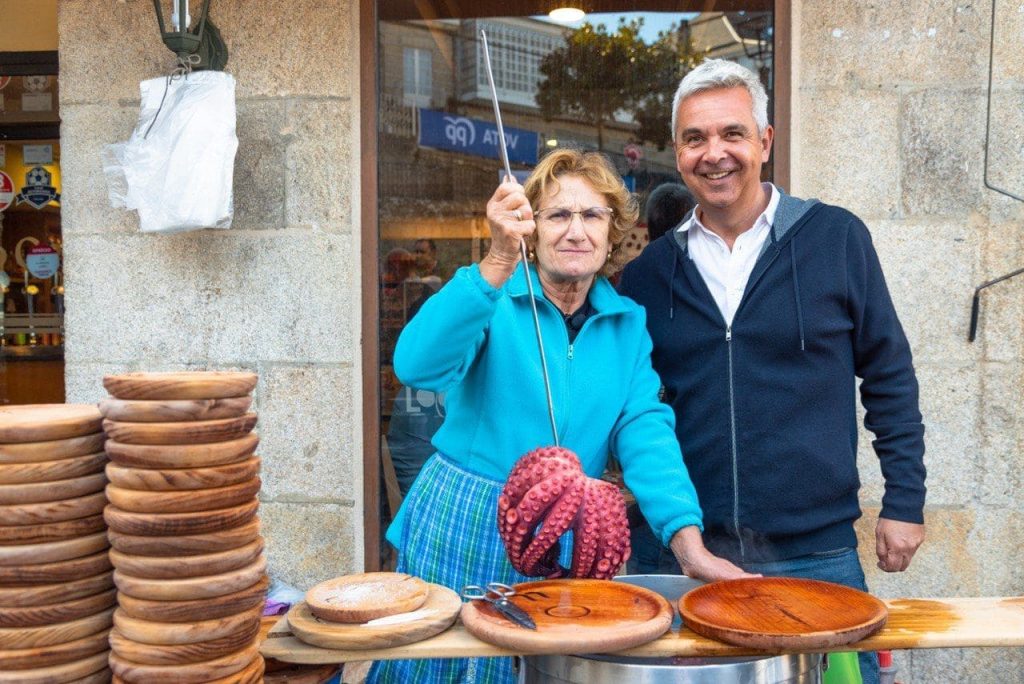 Juan Carlos Pérez, CEO de Aldealista con vecina gallega mostrando una elaboración de “pulpo a la gallega” en una especie de venta.