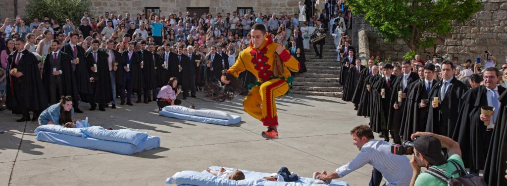 Un hombre disfrazado con un traje amarillo y rojo salta sobre bebés acostados en colchones en la calle durante la fiesta tradicional de El Colacho en Castrillo de Murcia.